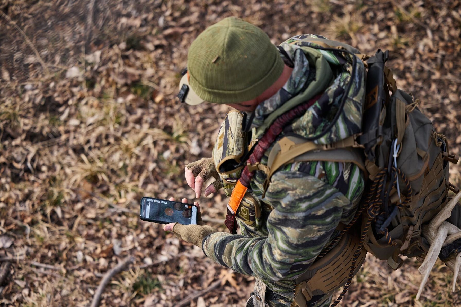 Hunter in camo using HuntWise, bow hunting elk concept.