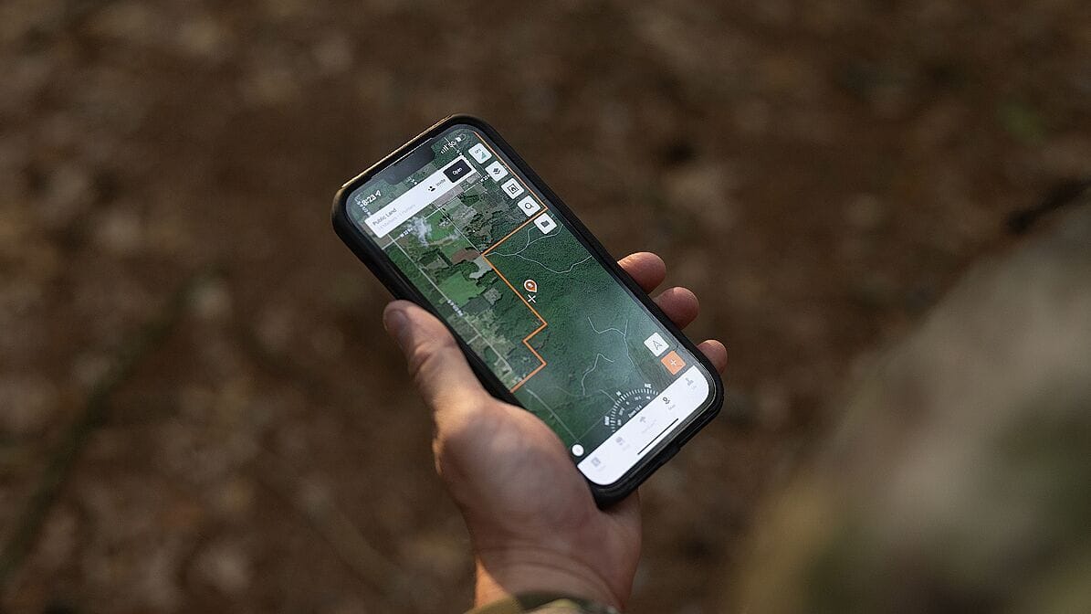 Hand holding a phone showing HuntWise maps, how to find property lines for hunting concept.