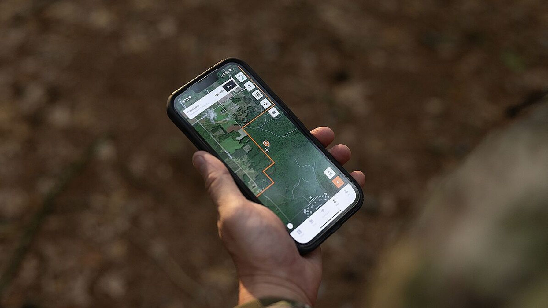 Hand holding a phone showing HuntWise maps, how to find property lines for hunting concept.