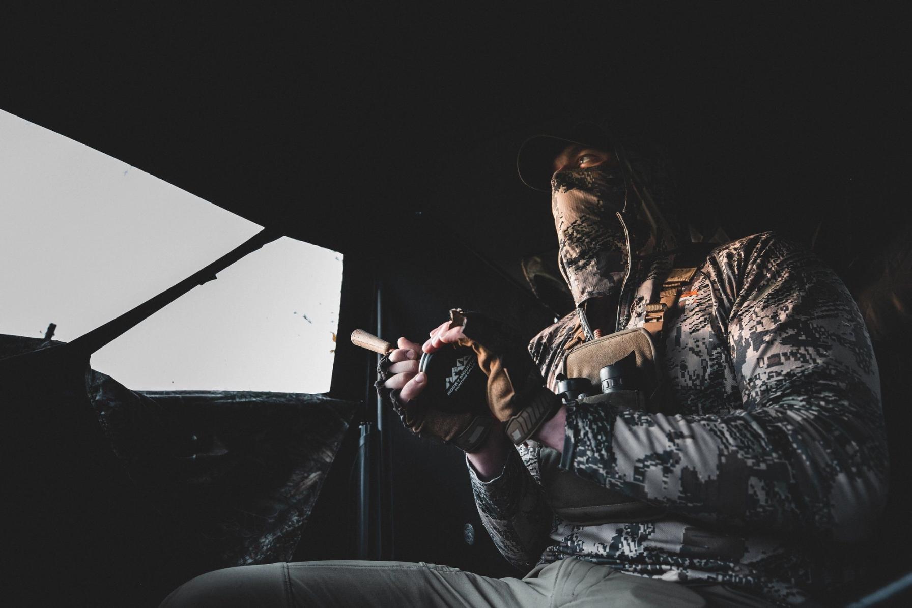 Hunter in a turkey blind uses a slate call.