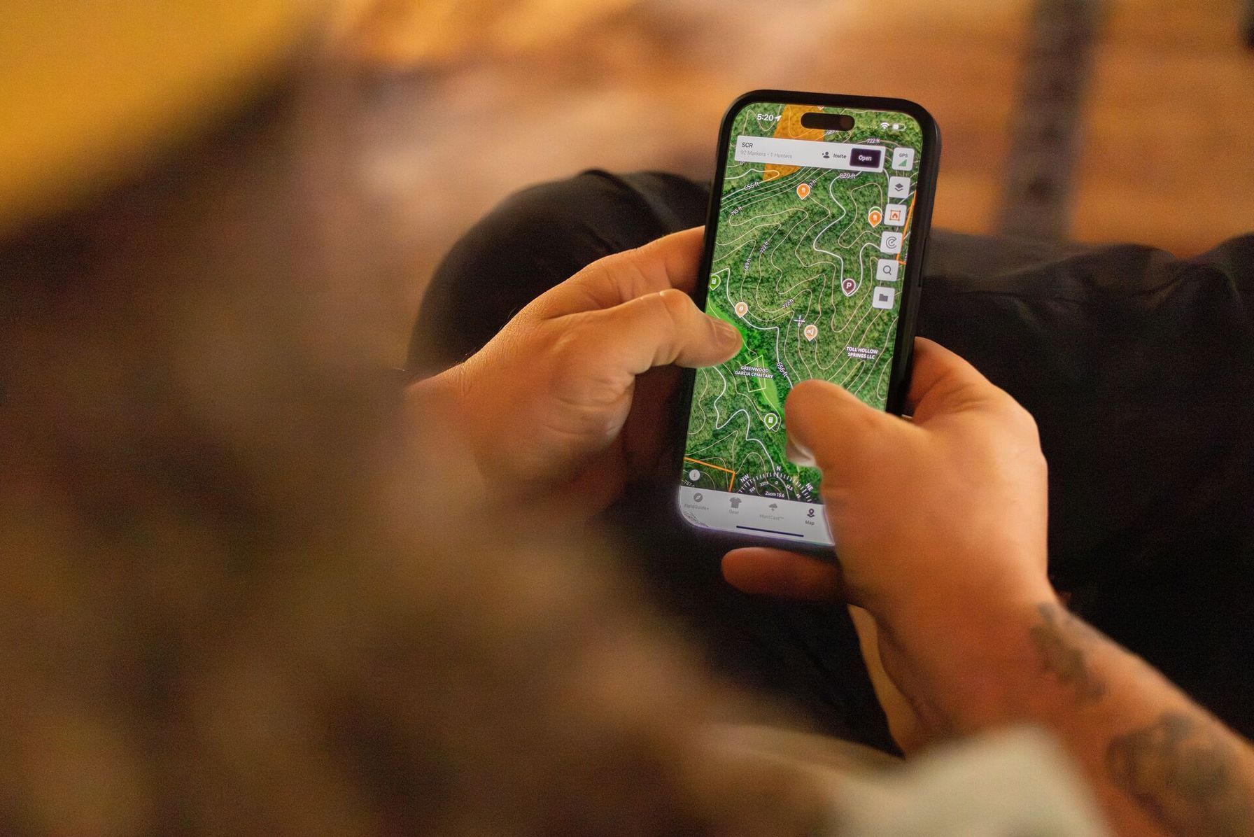 Hunter looks at HuntWise maps on a phone screen, hunting private land concept.