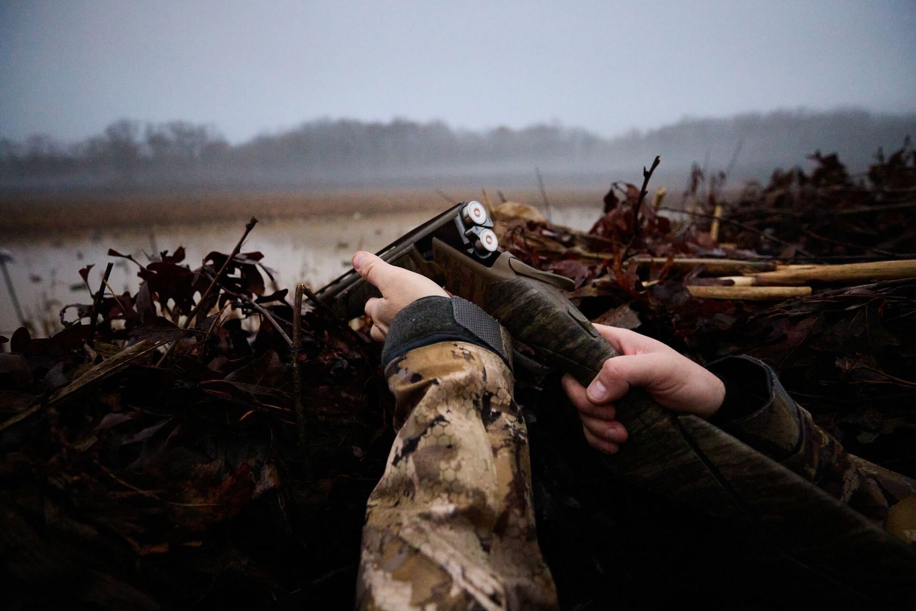 Hunter opens shotgun to reload while in duck blind, shotgun for hunting concept.