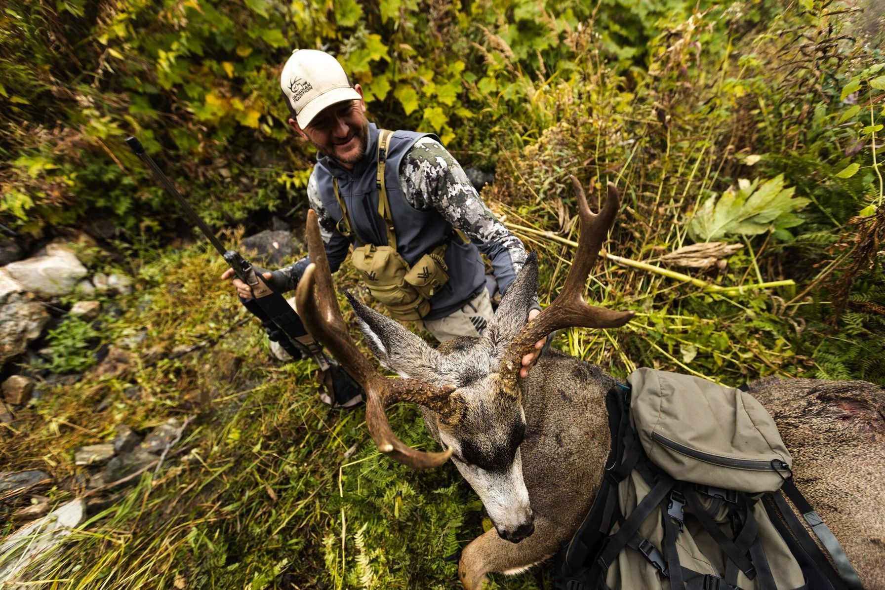 Hunter smiling with rifle and buck deer after a hunt, field dress a deer concept.