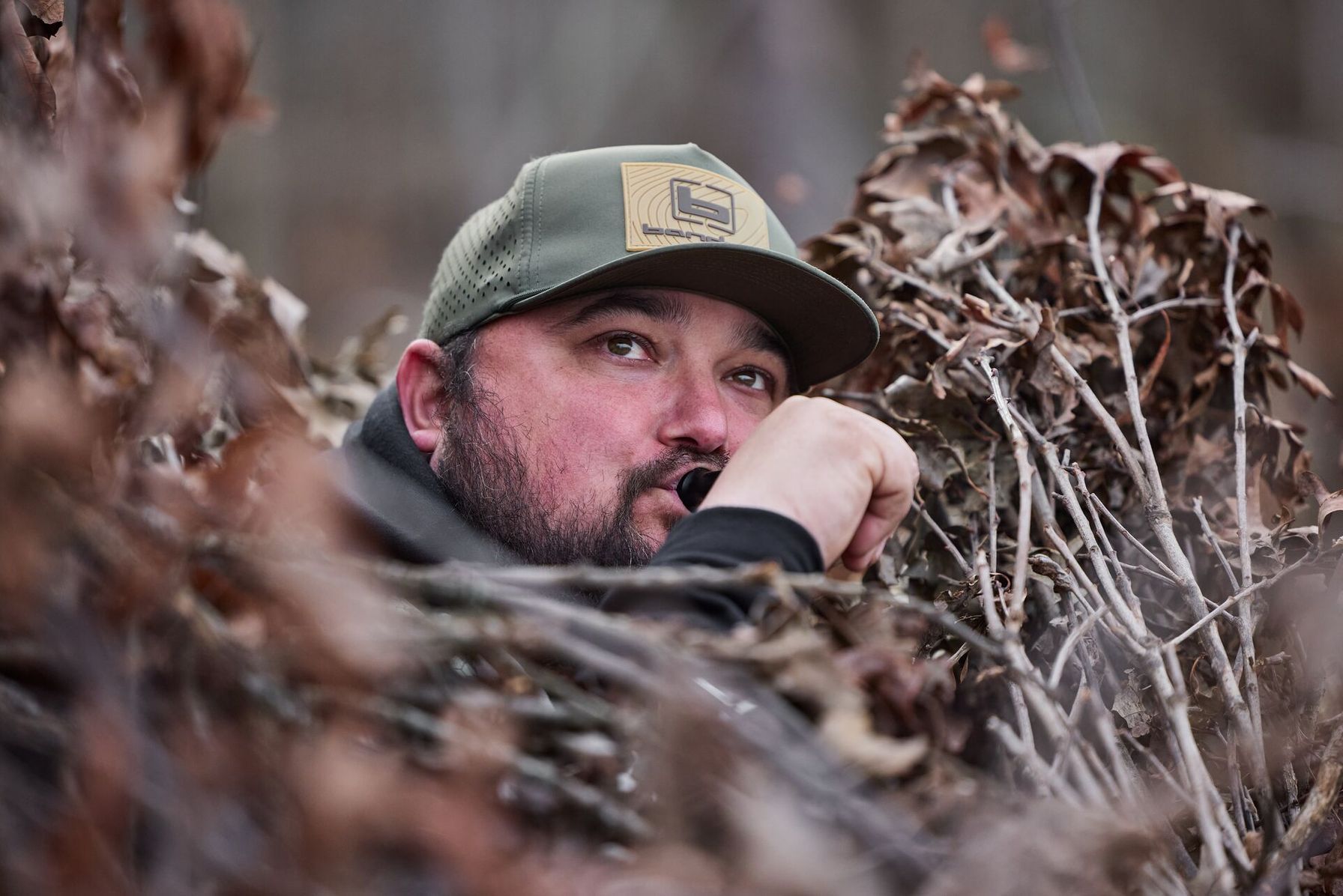 Hunter using duck call in blind, find public waterfowl hunting land Iowa concept.