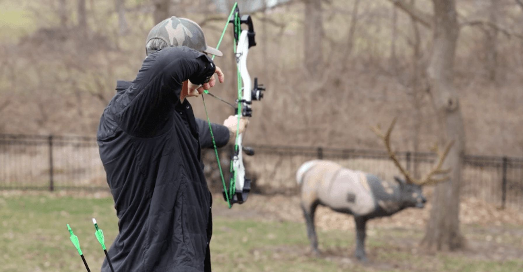John Dudley at full draw aiming a compound bow at a target.