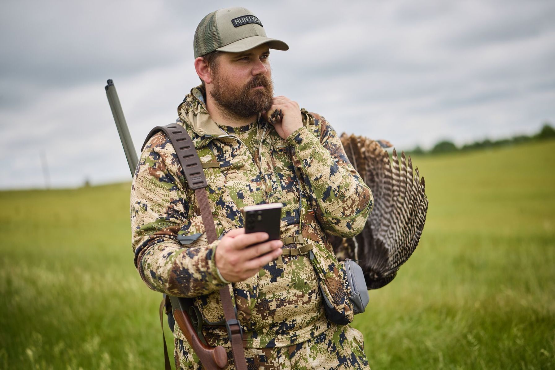 Hunter with turkey gear and phone for HuntWise turkey scouting.