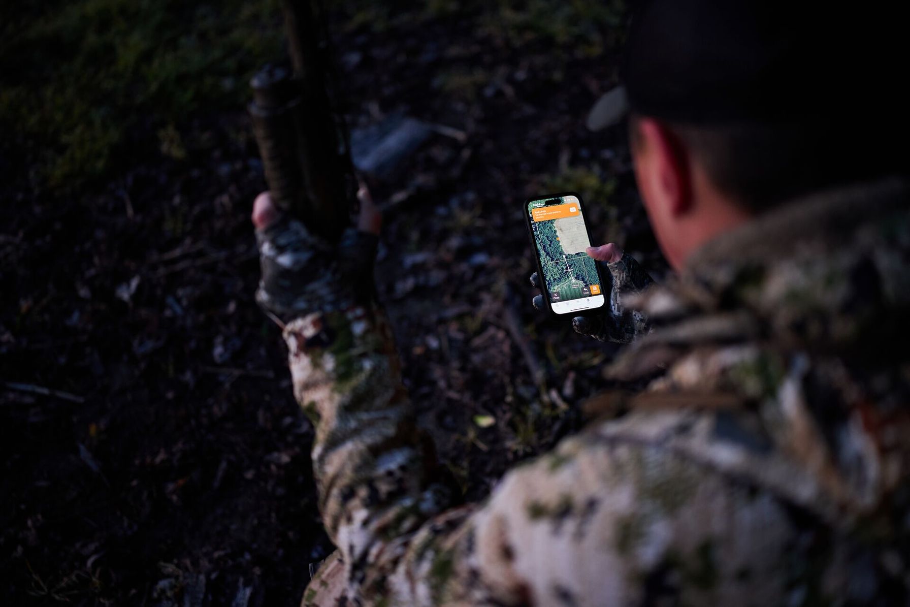 Hunter looking at phone showing the HuntWise hunting app, public land hunting concept.