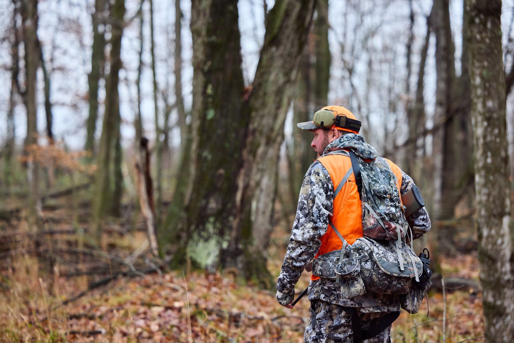 Hunter walking in the woods while wearing blaze orange, walk-in hunting access in Texas concept.