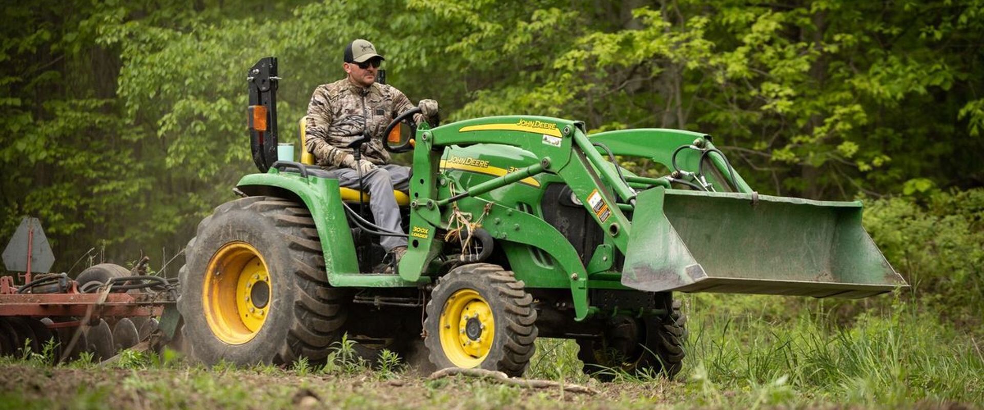 A hunter uses a tractor to clear land, when to plan spring food plots for deer concept.