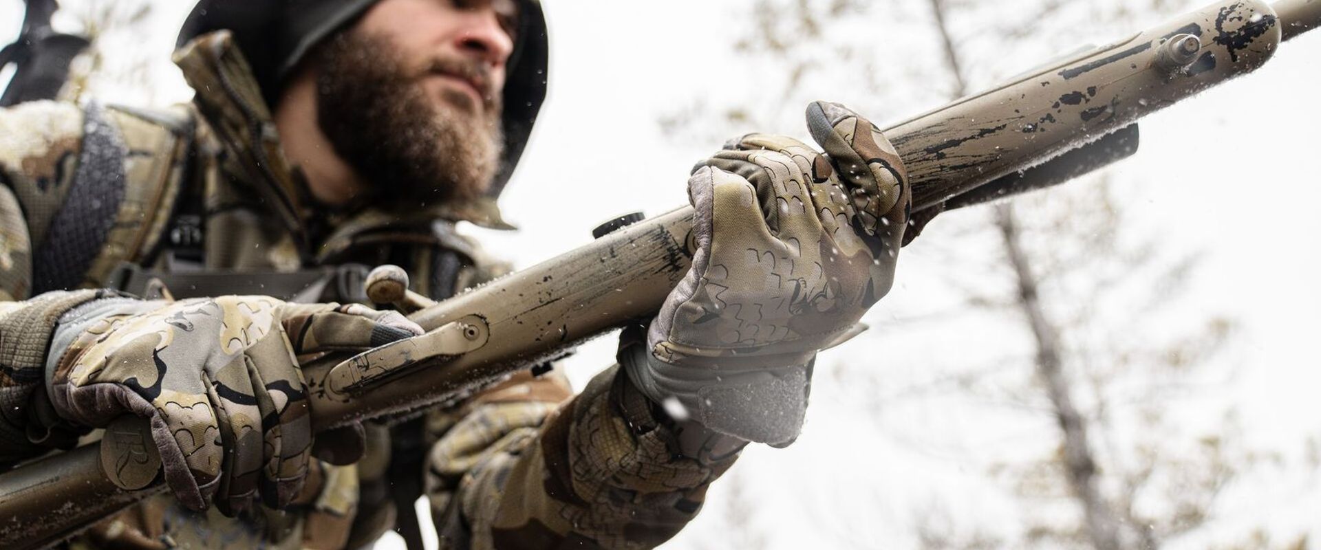 A hunter in camo holds a rifle, understanding hunting shooting positions concept.