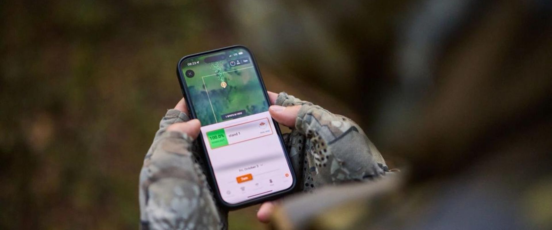 FGBLOG hunter looks at phone showing HuntWise WindCast