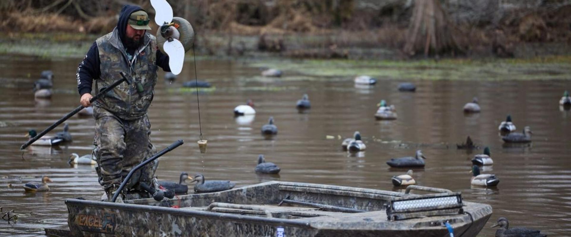 Hunter in boat sets out decoys, duck decoy hunting concept.