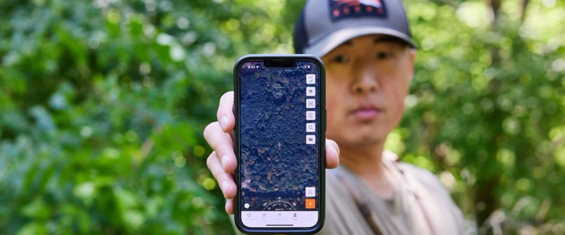 A hunter holds up a cellphone with the HuntWise hunting app on screen, prepare for hunting season concept. 