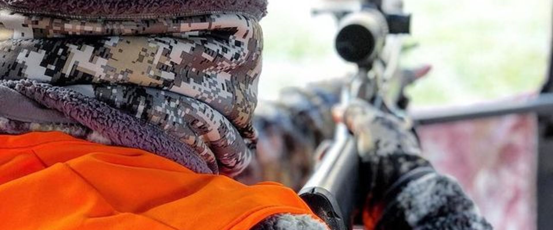 A hunter with gear and bow walks on hunting land.