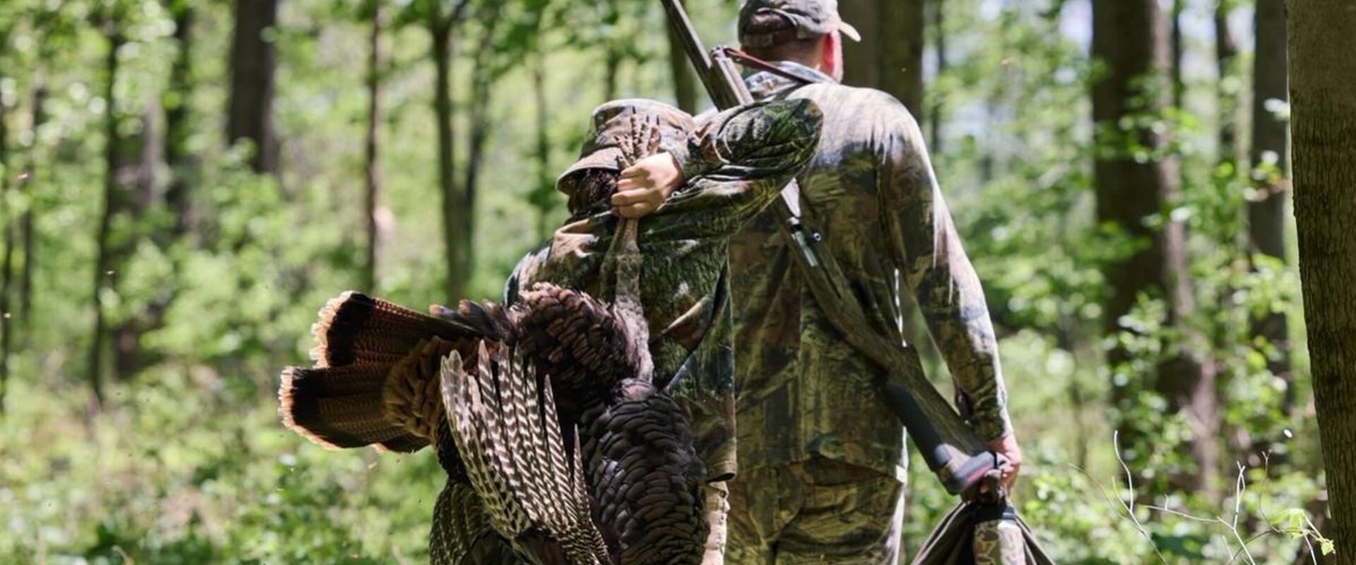Boy carries turkey with man after hunt, turkey hunting season South Carolina concept.