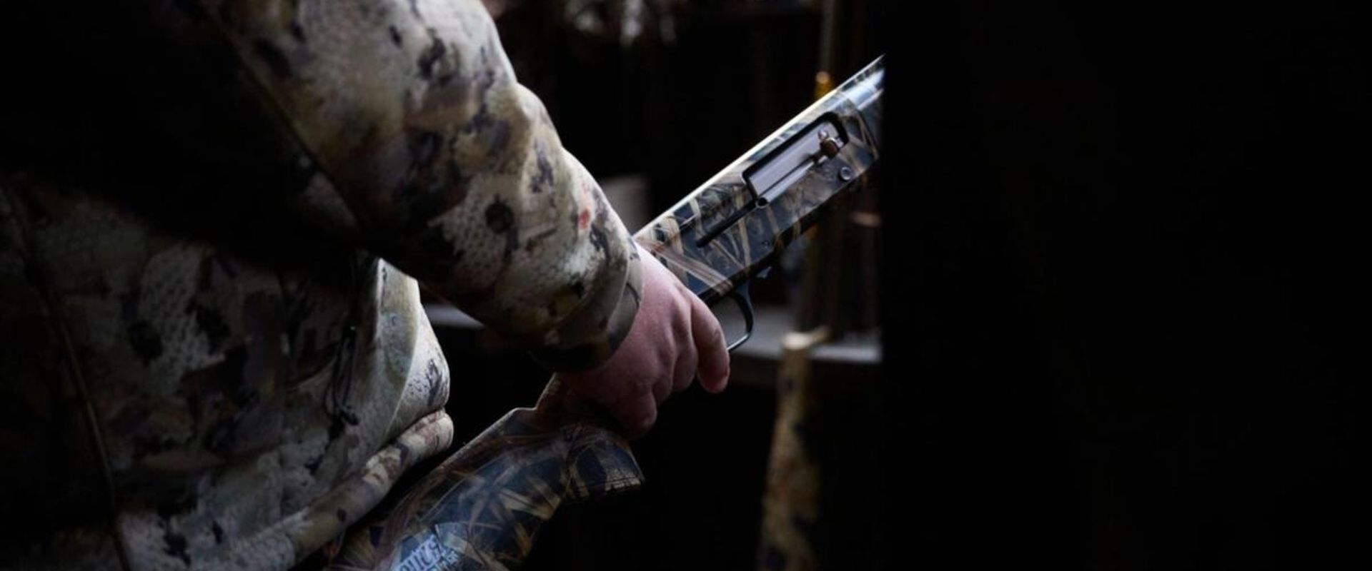 Hunter with shotgun in duck blind, waterfowl shotguns concept.