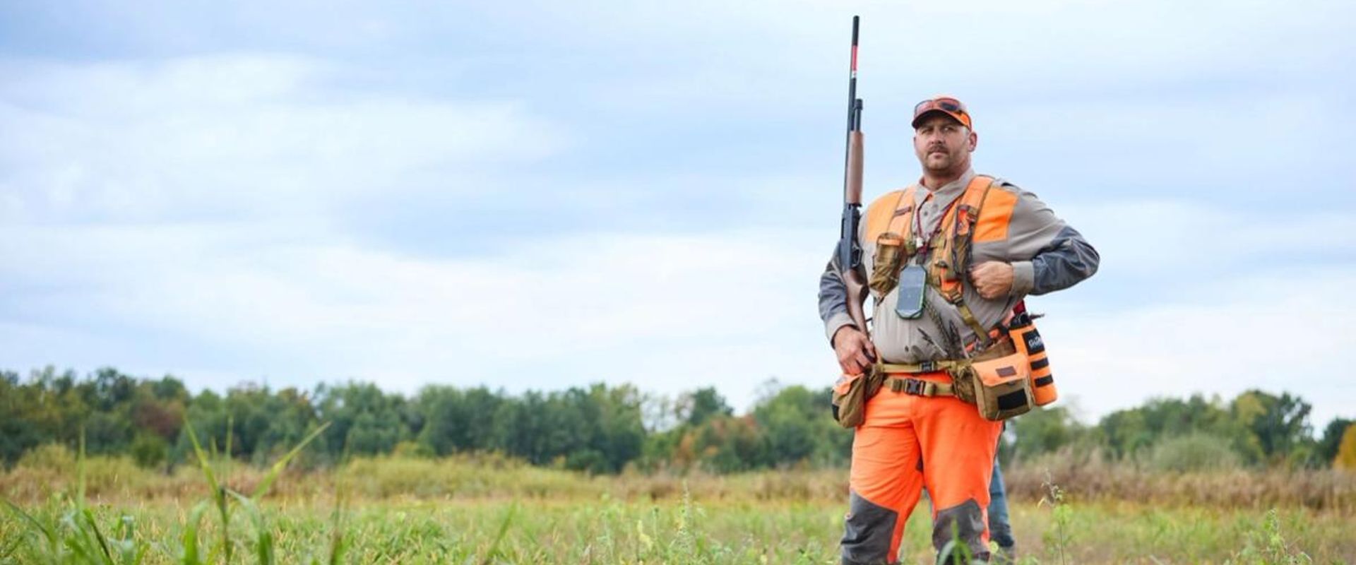 Hunter with shotgun in blaze orange for upland hunt, how to find walk-in hunting in Illinois concept. 