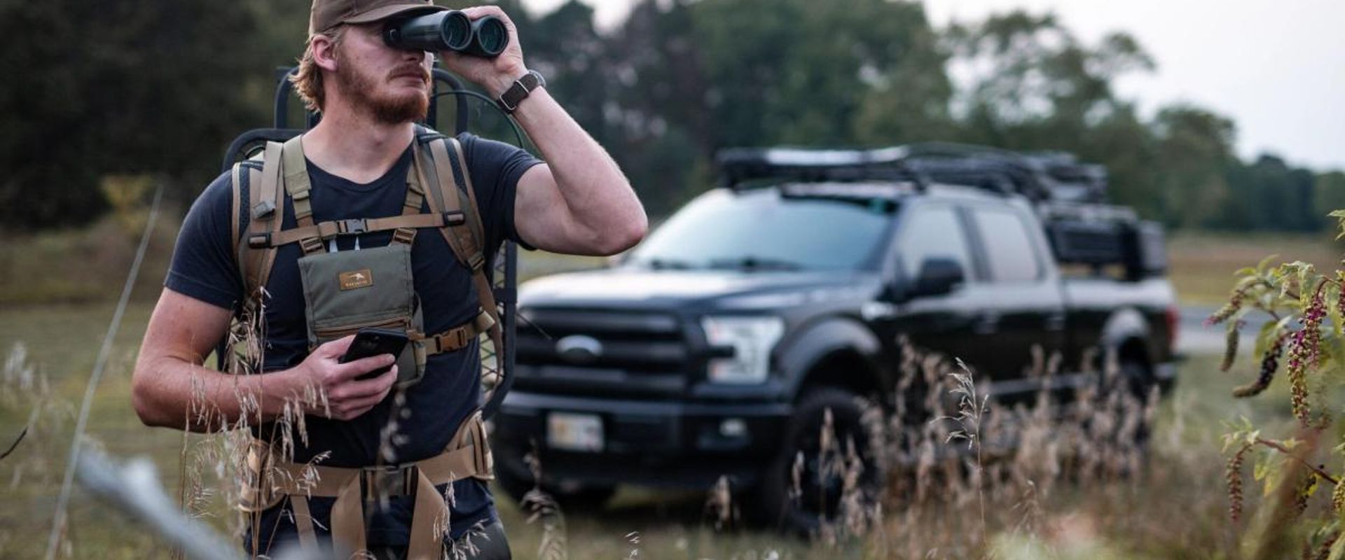 A hunter uses binoculars when scouting for deer.