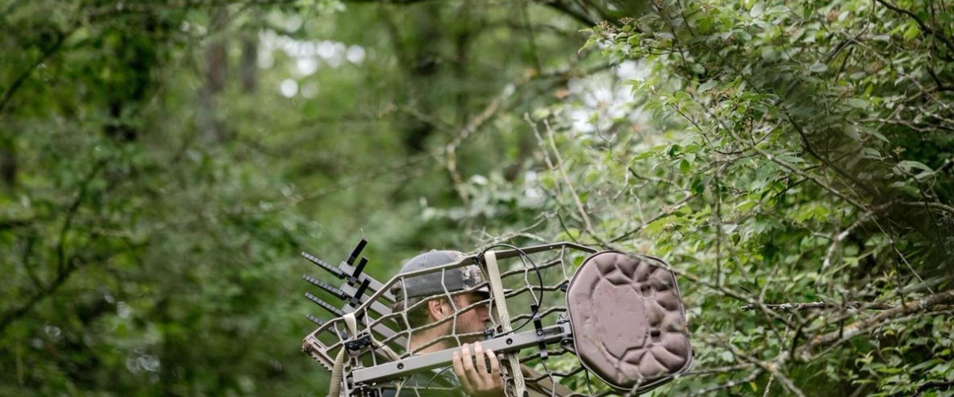A hunter carries a tree stand, hang on treestand vs climber concept.