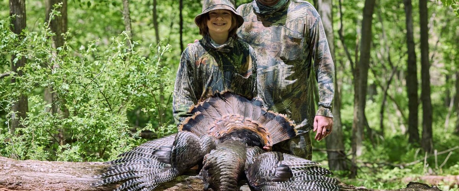A dad and son in camo after a turkey hunt, hunting gifts for dad concept.