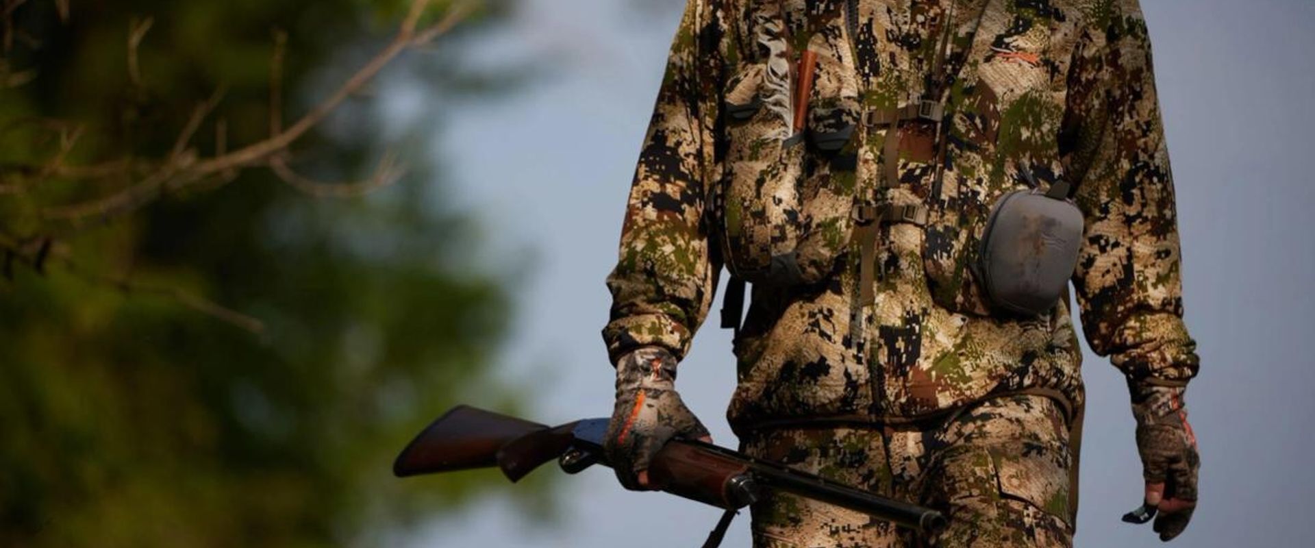 A hunter in camo holding a rifle in the field, get a Mississippi hunting license concept.