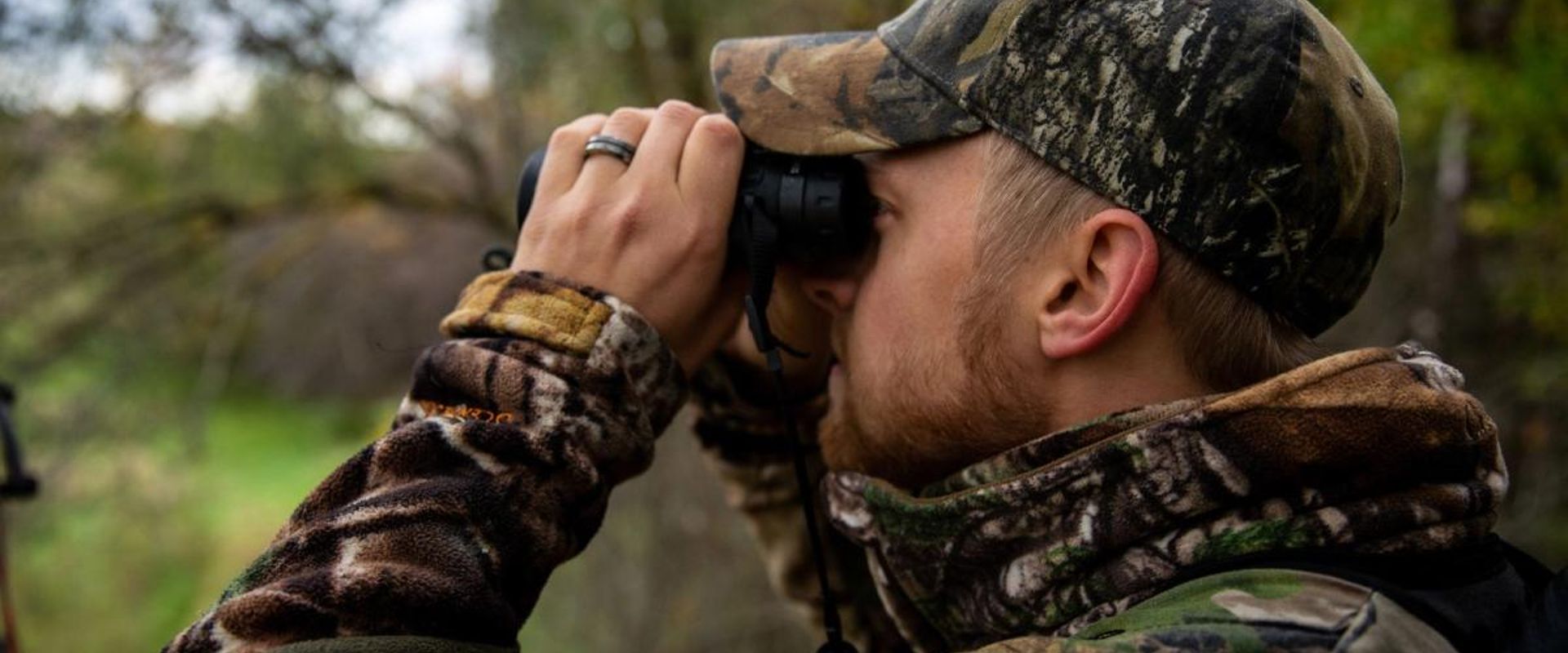 A hunter using binoculars, how to scout for deer land.