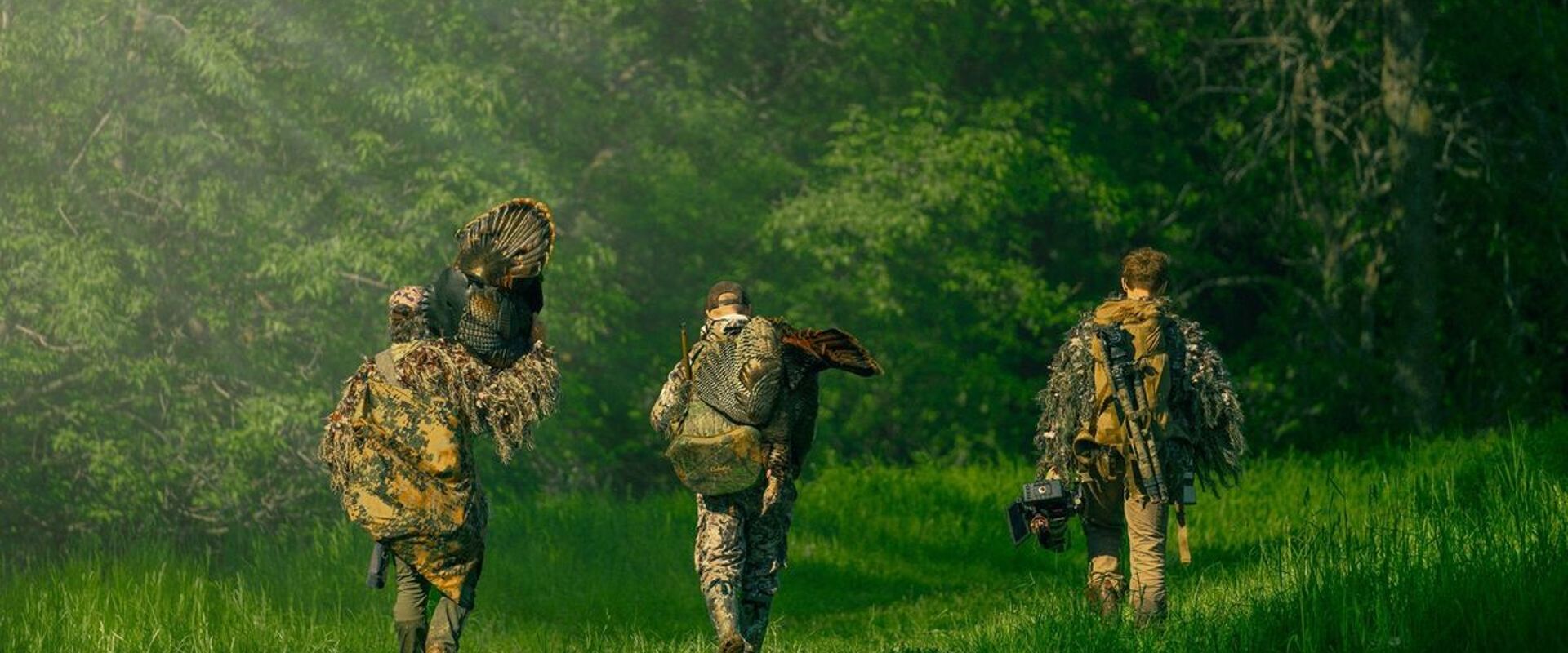 Three hunters from Blueline Bowhunters walking, one carries a turkey, turkey hunting tips concept.