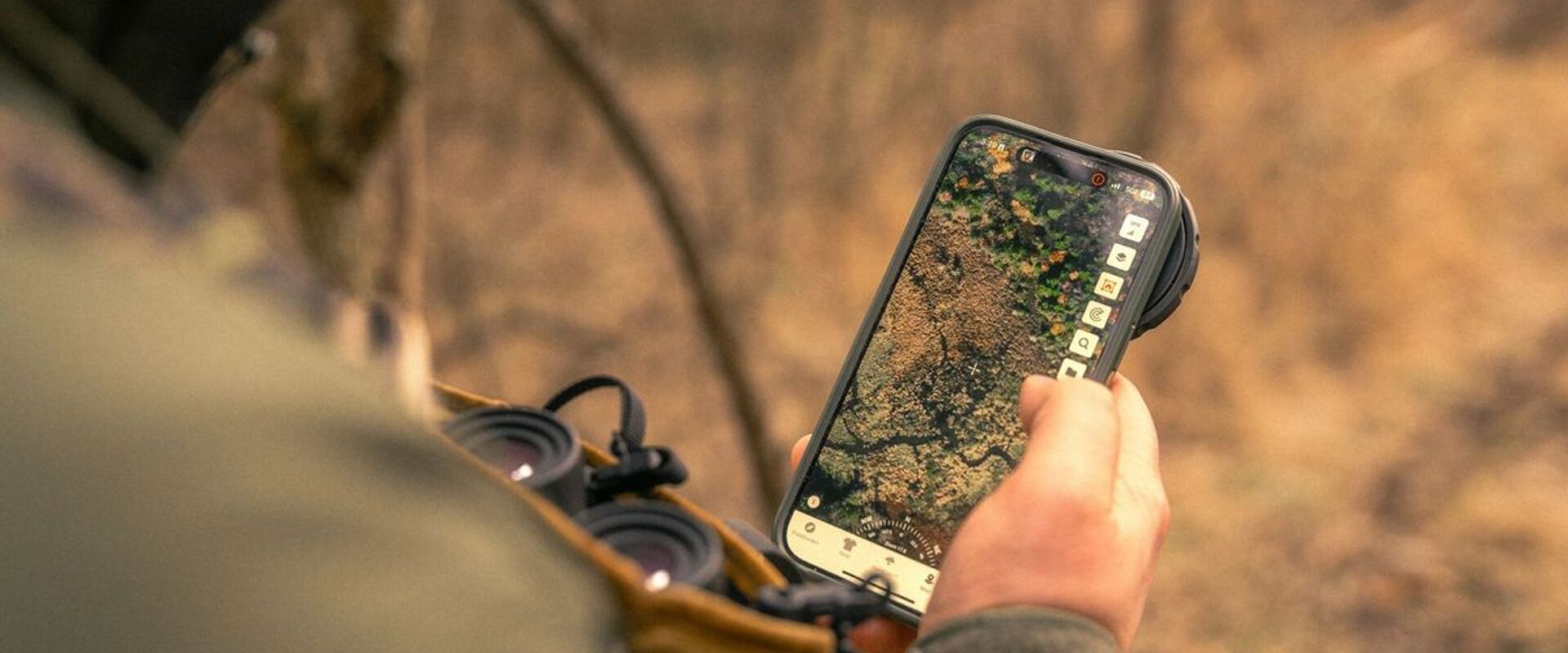 Hunter with phone in hand showing HuntWise on screen, e scouting for elk concept.
