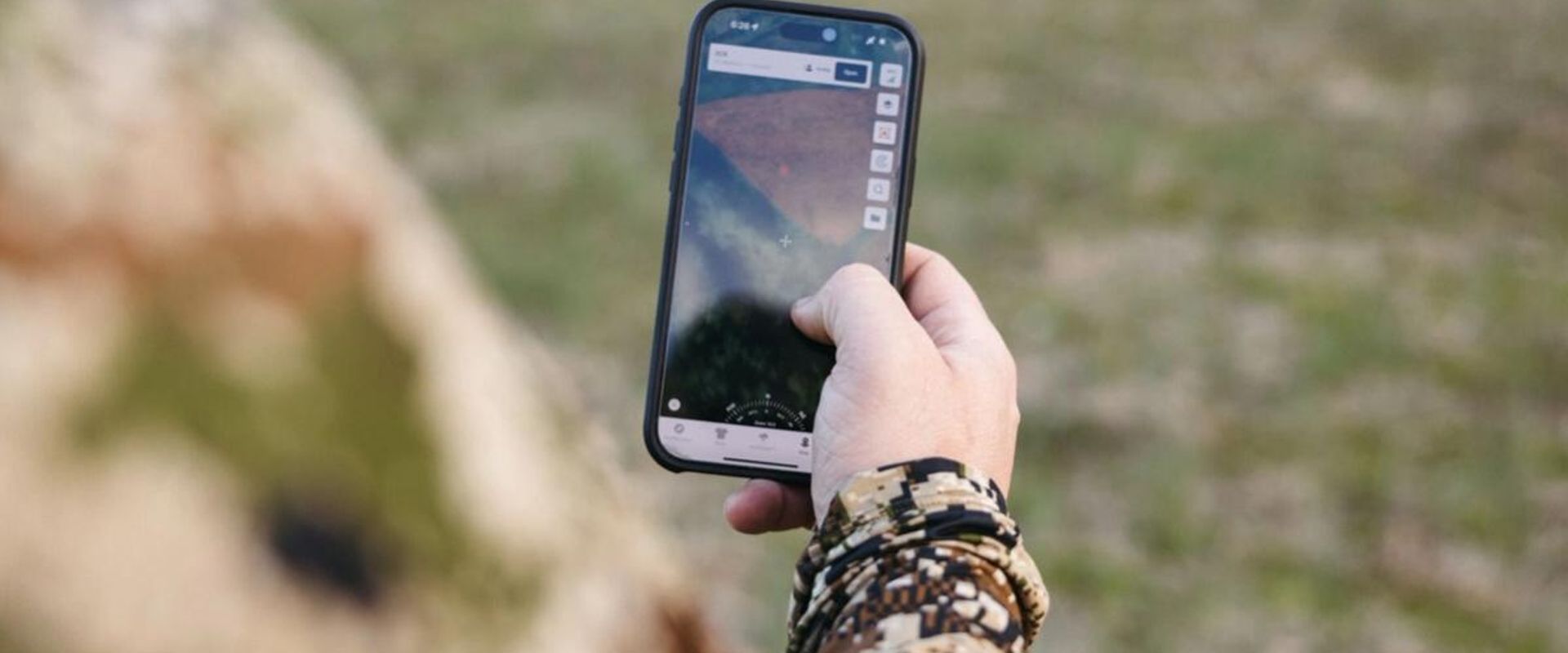 Hunter looking at phone to use topographic map app HuntWise.