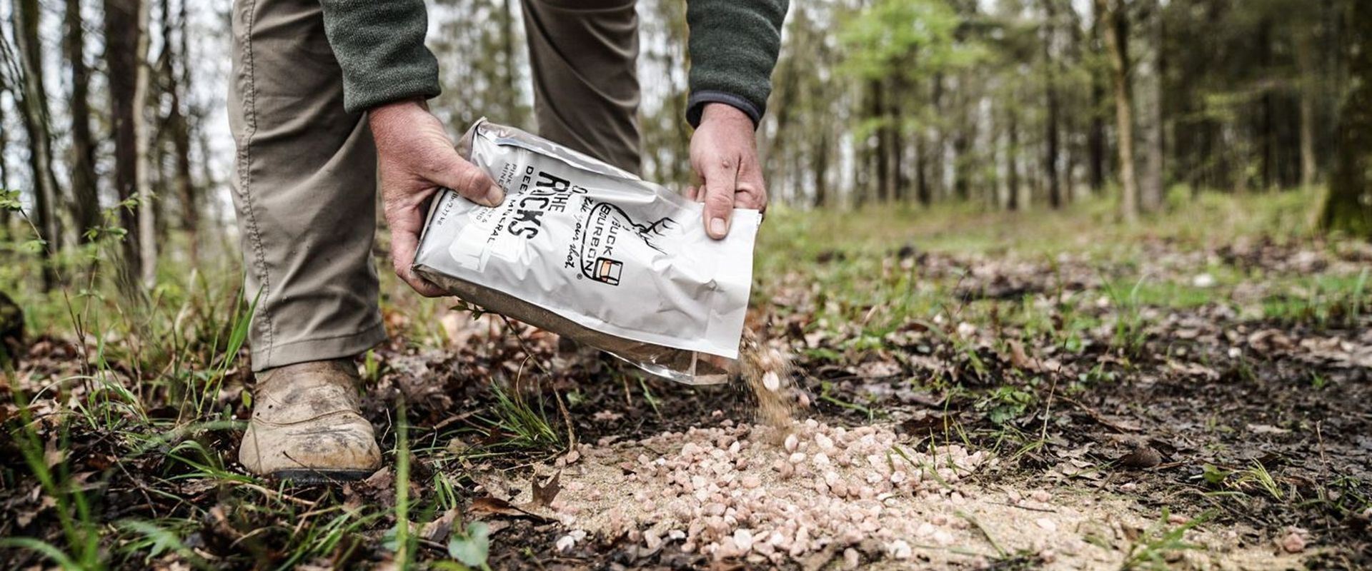 Hunter pouring minerals onto ground, deer mineral site concept.