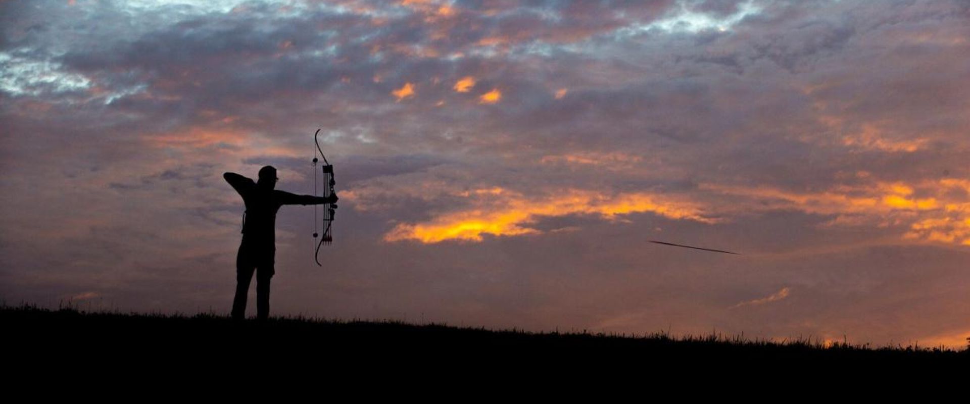 A bowhunter in the distance draws the bow, hunting whitetail deer concept.