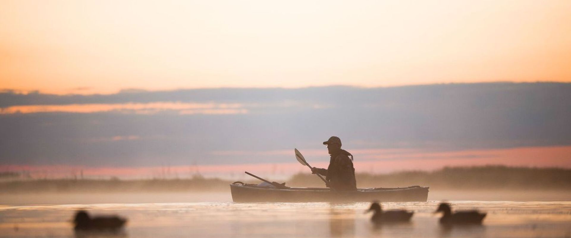 Hunter in canoe on water near waterfowl decoys, public waterfowl hunting land in Ohio concept.