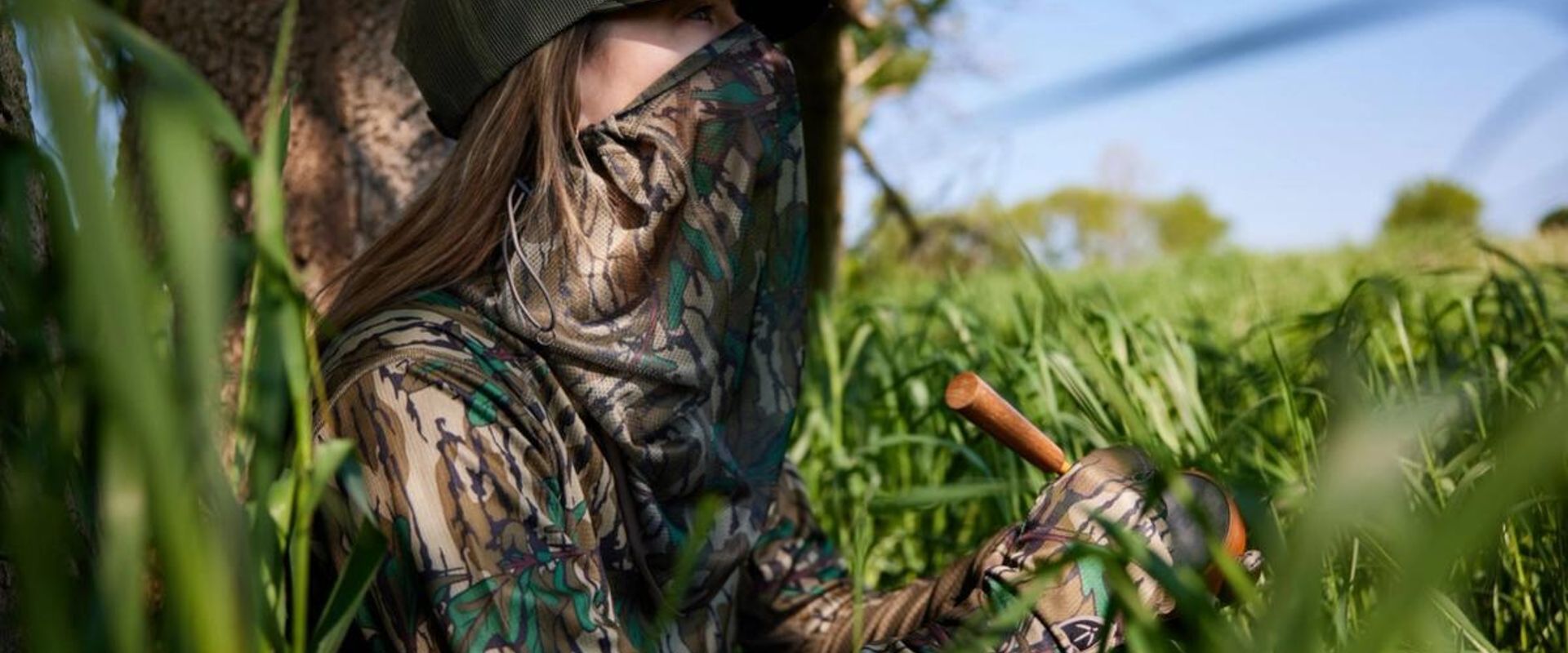 Female hunter uses a slate turkey call in the woods, best turkey calls for beginners concept.