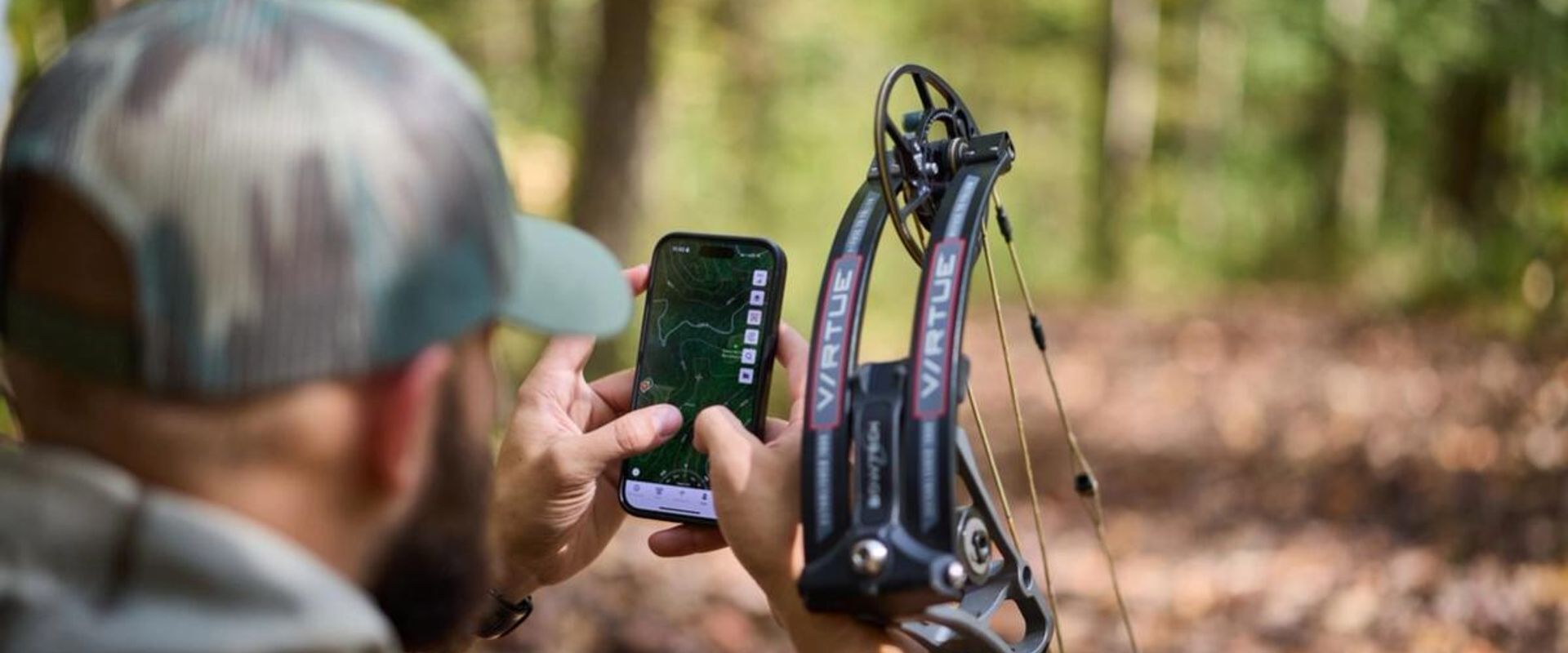 Hunter with bow using phone showing HuntWise on screen, how to use a hunting app concept.