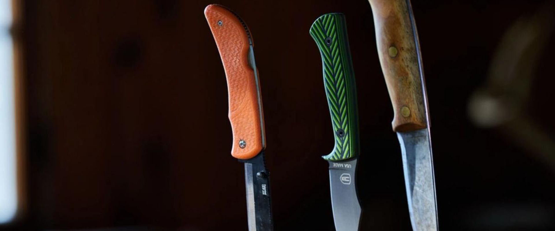 Three hunting knives stuck into a wood stump, choosing hunting knives concept.