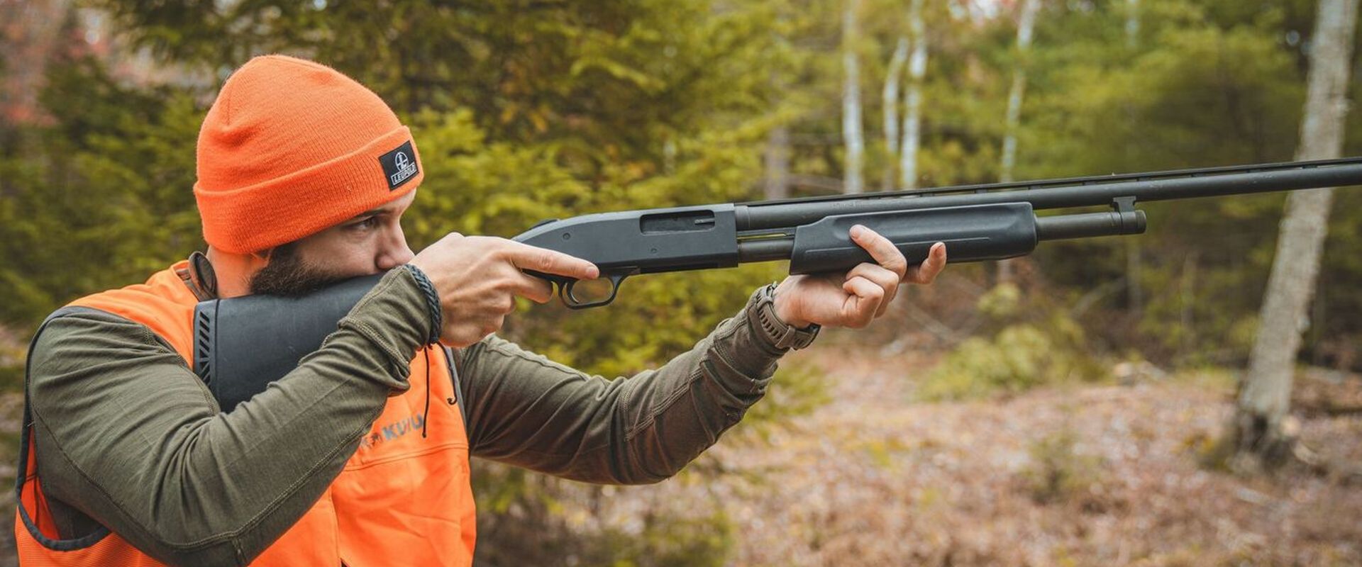 Hunter in blaze orange aims shotgun, find the best dove hunting near me concept.