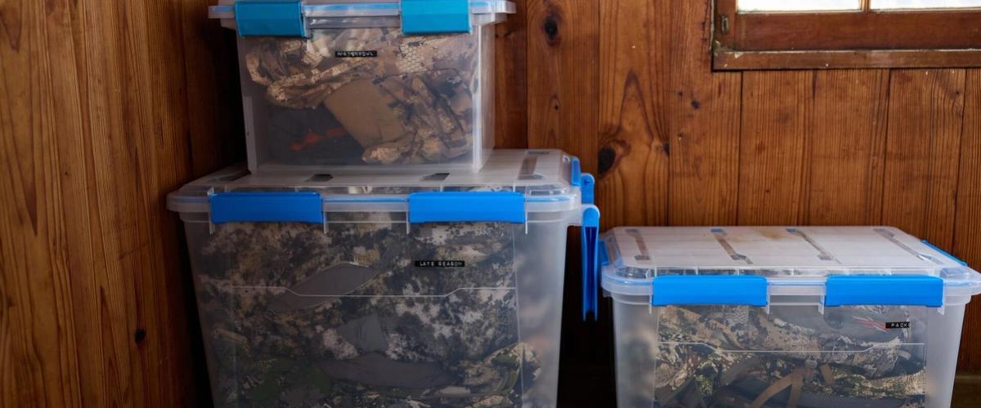 Hunting gear storage containers stacked against a wall.