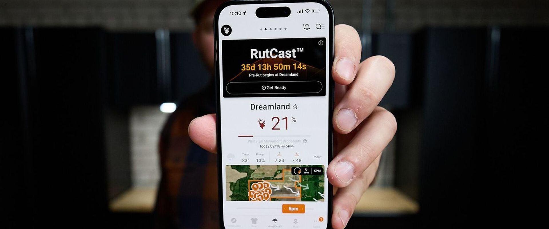 Hunter holds a phone showing RutCast on screen, RutCast hunting concept. 