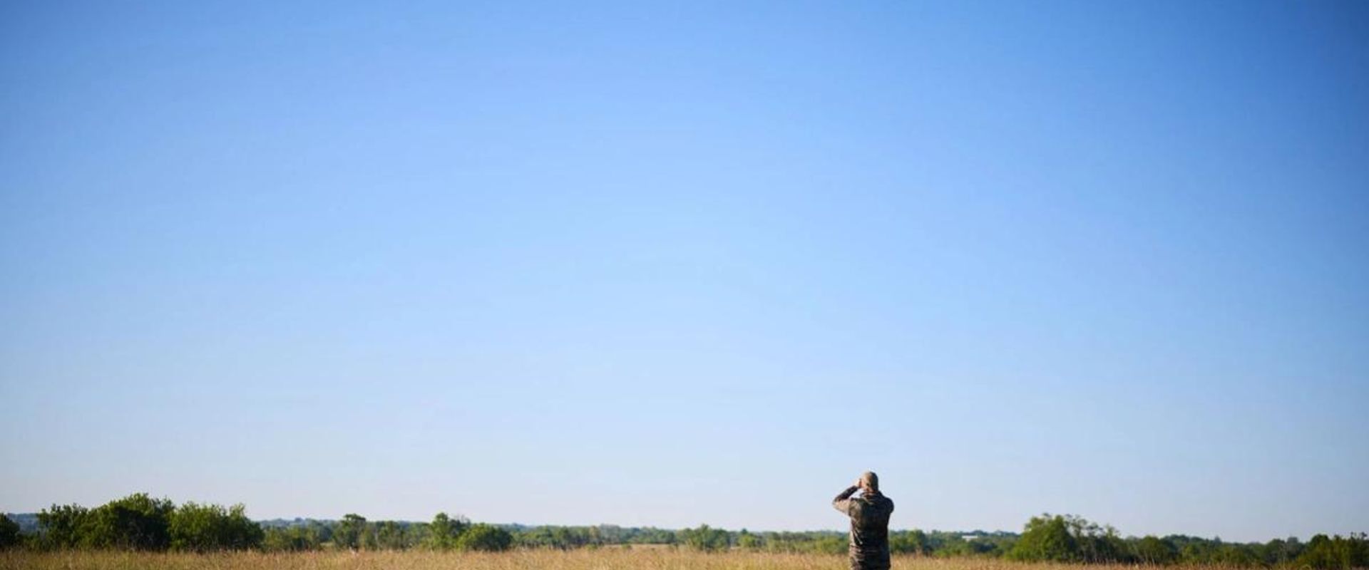 Hunter in a field in the distance, how to find walk-in hunting in Texas concept. 