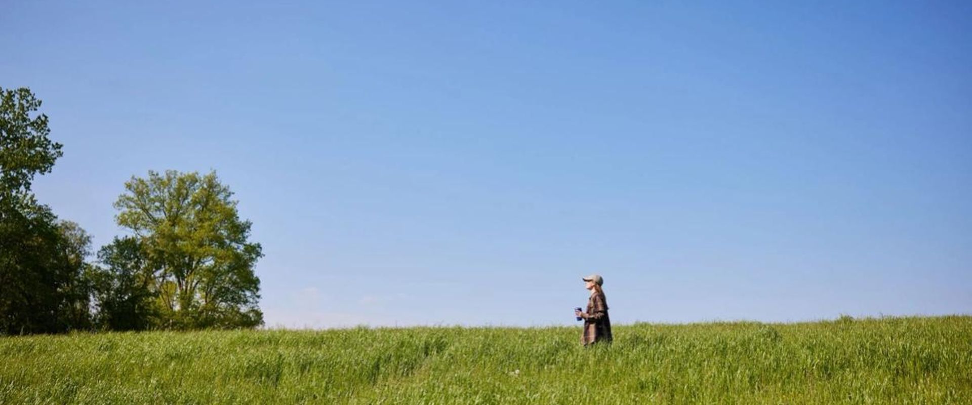 A woman in a green field, looking for private hunting land near me concept.