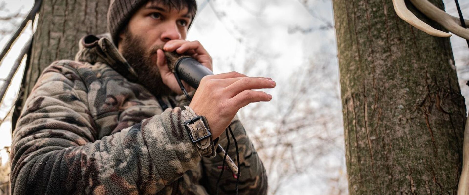 Hunter using deer call in the woods, types of deer calls concept.