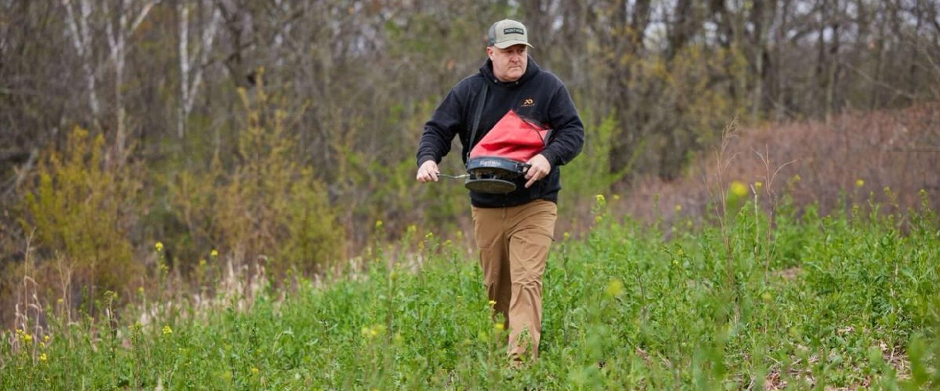 Jeff Sturgis with a seed spreader walks through a food plot, what do deer eat concept.