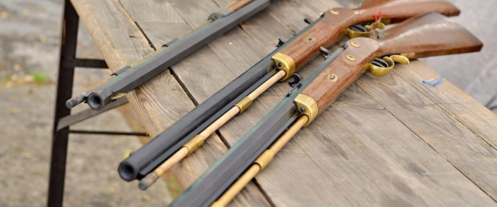 Three muzzleloader rifles on a table.