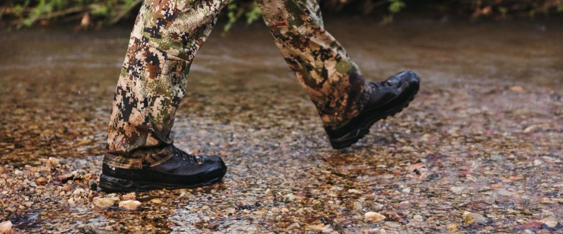 Close-up of a hunter's boots as he walks through water, summer huntingn boots concept.
