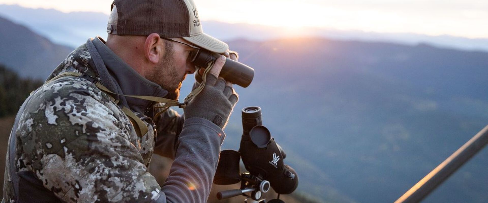 Hunter glassing on hill, high country mule deer hunting concept.