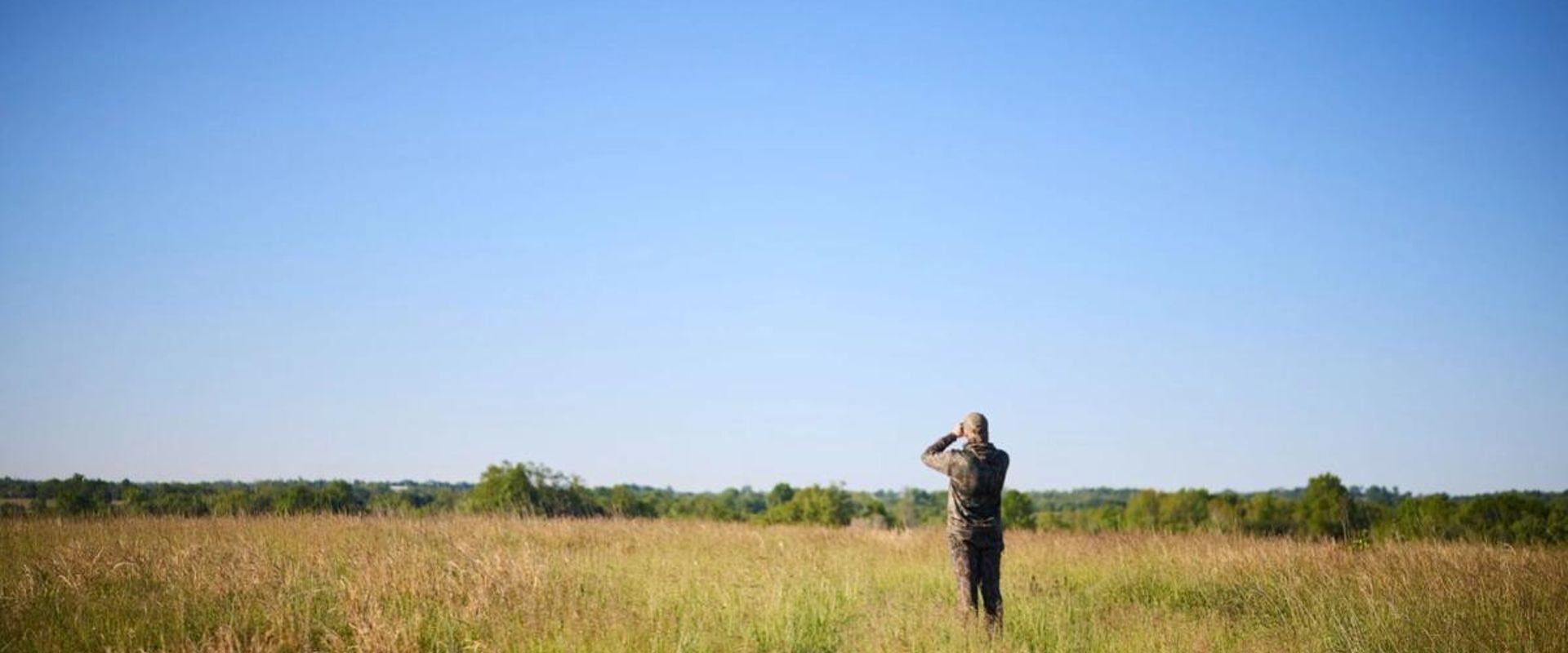Hunter using binoculars in a field, how to find property lines in Minnesota concept. 