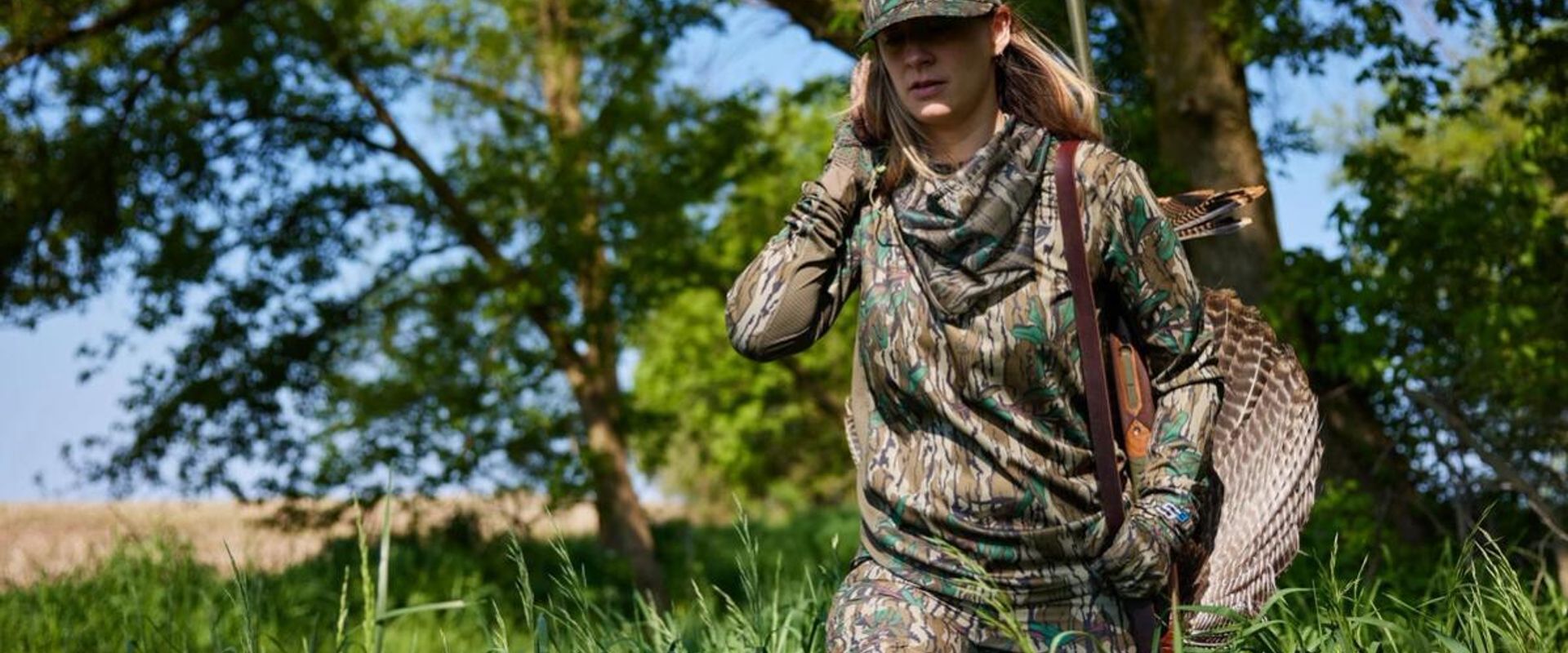 A female hunter carries a turkey after a hunt, hunting Wisconsin Turkey Zones concept.