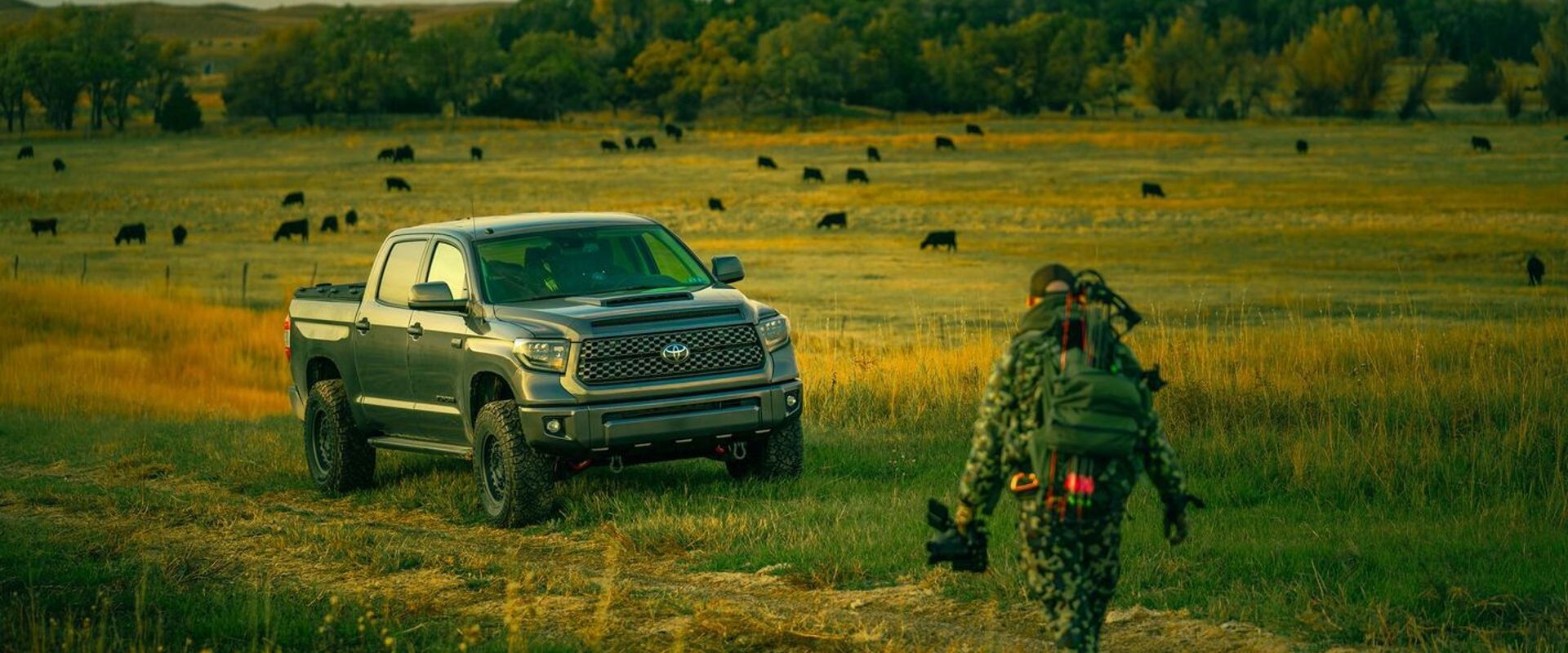 Hunter with gear walks toward truck in a field, leave no trace hunting concept.