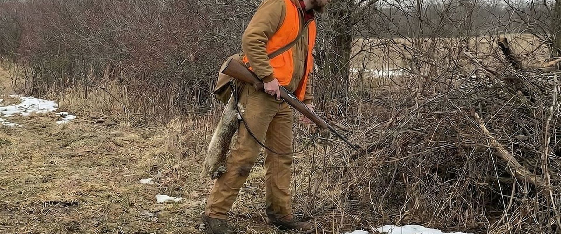 Hunter with rabbit on belt hunting in the woods, where to find rabbits concept.