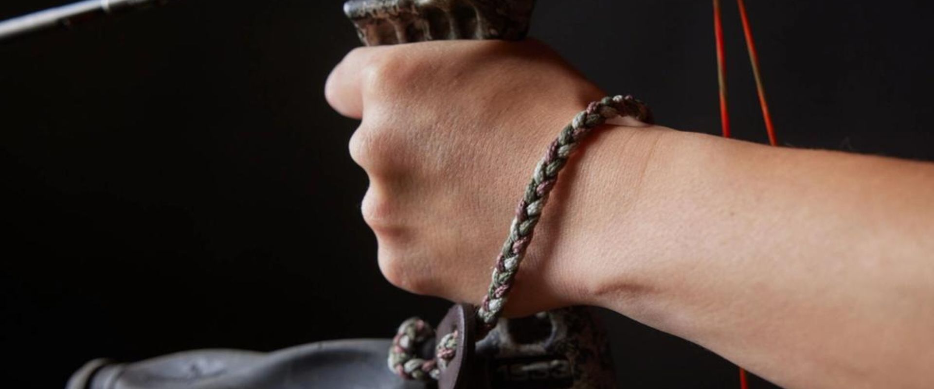 Close-up of a wrist bow sling on a wrist while holding a bow.